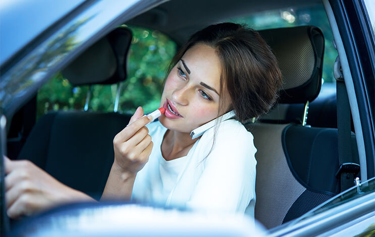 teenage girl distracted driving while putting on makeup