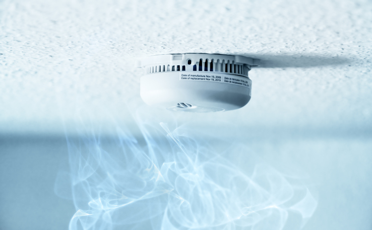 A smoke detector installed at a ceiling with smoke.