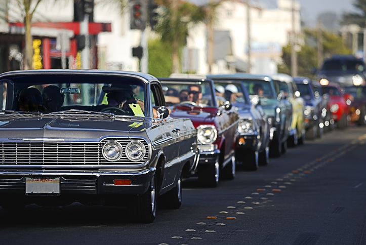 A line up of classic old cars cruising a local strip.