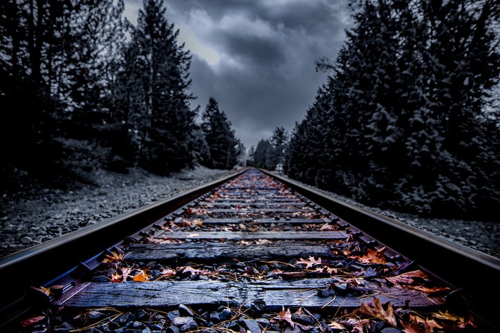 Dark abandoned railroad tracks with autumn leaves