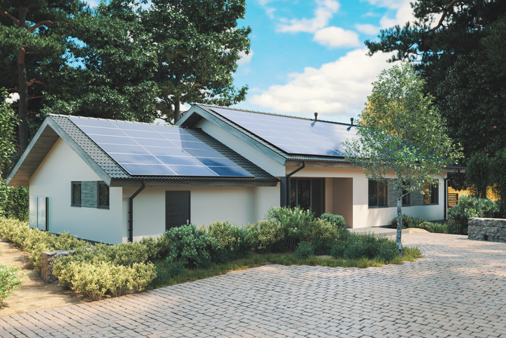Modern single story house with solar panels and wall battery for energy storage.